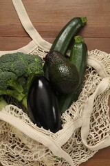 String bag with fresh vegetables and avocado on wooden background, top view