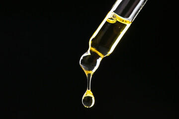 Dripping tincture from pipette on black background, closeup. Space for text