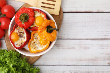 Delicious stuffed peppers in bowl, ingredients and spatula on white wooden table, flat lay. Space for text