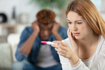 troubled upset couple looking at pregnancy test