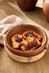 Cozy Autumn Meal: Woman Enjoying Fried Cheese with Cranberry Jam in a Rustic Kitchen Setting