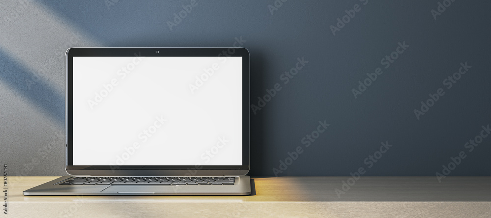 Poster close up of empty white computer monitor on simple wide wooden desk. blue wall background. workplace