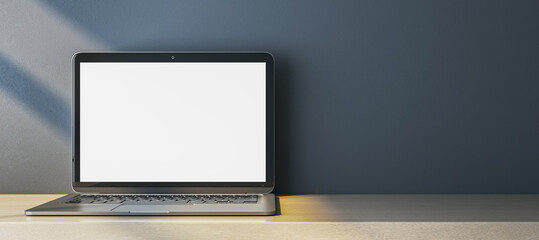 Close up of empty white computer monitor on simple wide wooden desk. Blue wall background. Workplace concept. Mock up, 3D Rendering.