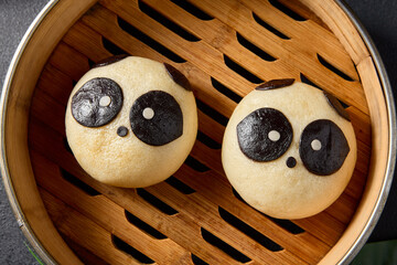 Top view of adorable panda bao buns in a bamboo steamer, an example of delightful Asian edible...