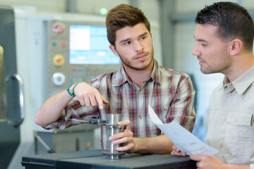 apprentice measuring diameter of metal cylinder with caliper set