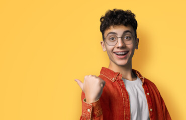 Excited happy black curly haired man in braces, open mouth wear glasses orange shirt advertise show...