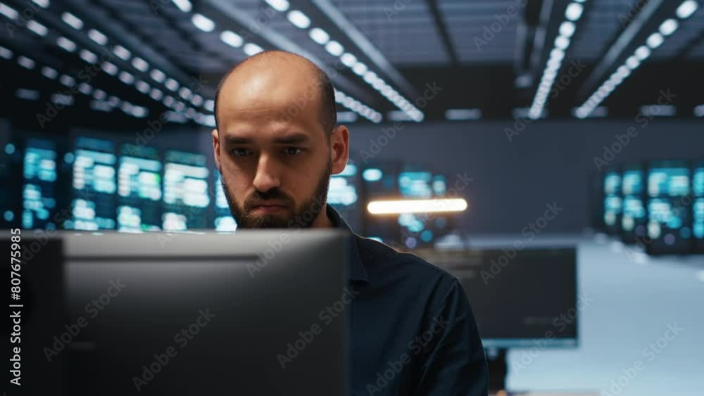 Poster man in server room typing code, ensuring data remains shielded from threats. panning shot of it tech