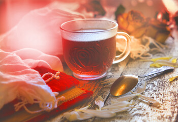 Cup of tea with white flowers petals on wooden table, vintage effect, retro toned, atmospheric mood. Morning soft light. Rustic style
