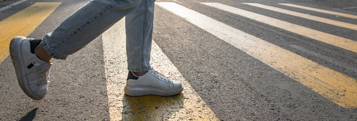 Man's legs crossing the road, yellow lines stock photo