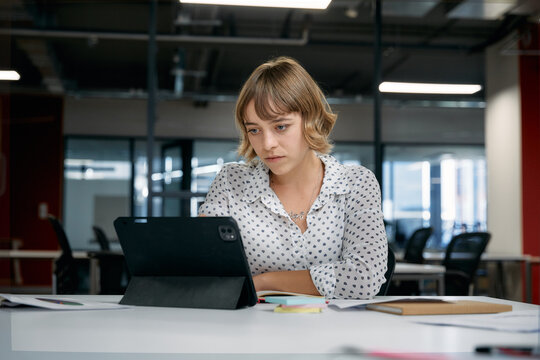 Focused young caucasian businesswoman using digital tablet during meeting in office