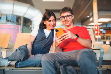 Relaxed couple in airport terminal waiting for plane at sunset, while checking travel reservations...