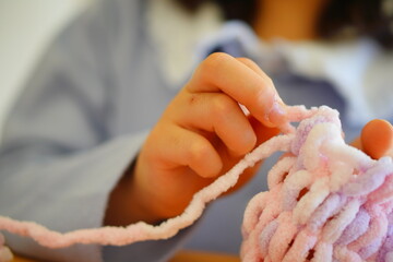10歳 小学4年生の女の子が指編みで編み物をしている様子。