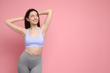 Happy young woman with slim body posing on pink background, space for text