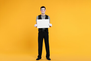 Funny mime artist with blank sign on orange background