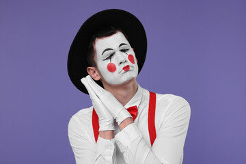 Mime artist in hat posing on purple background