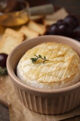 Tasty baked camembert in bowl on table, closeup
