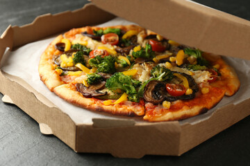 Delicious vegetarian pizza with mushrooms, cheese and vegetables in box on black table, closeup