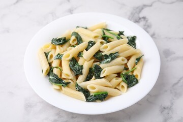 Tasty pasta with spinach and sauce on white marble table