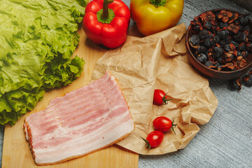 Sliced pork ham on a cutting board with vegetables and salad, prepared to cook lunch or breakfast.