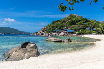 Peaceful tropical scenic landscape of Koh Nang Yuan Island in Thailand, near Koh Tao. An empty sand beach and crystal-clear sea water, with a hotel resort on the hillside by the shore