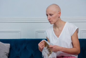 Sad middle aged woman cancer survivor holds wig in her hands