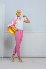 Smiling girl in superhero outfit concept of breast cancer fight