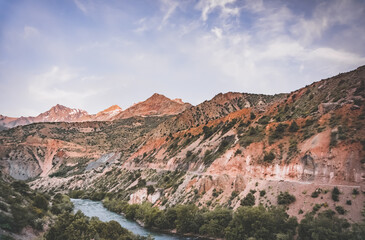 Rocky valley of the Iskanderdarya river with colorful red rocks and blue water of the river in the...