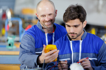two worker holding voltmeter smiling