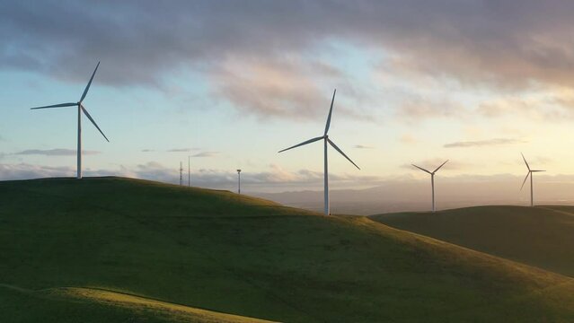 Wind Turbines Spinning on Hillside at Sunset