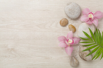 Composition with orchids and massage stones on wooden background, top view