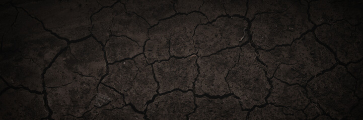 Texture of cracked dried soil. Dark wide panoramic background. Dry ground with cracks. Dark brown...