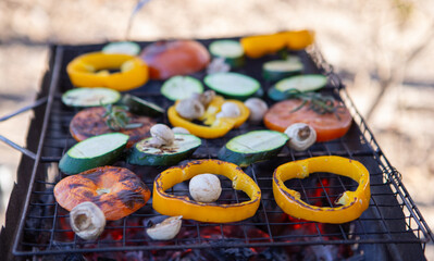 Fototapeta na wymiar Sliced fresh vegetables arranged on a grill for cooking, including tomatoes, zucchini, peppers, and mushrooms. Grilled vegetables freshly prepared over hot coals.