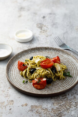 Spaghetti with pesto, tomatoes and olives