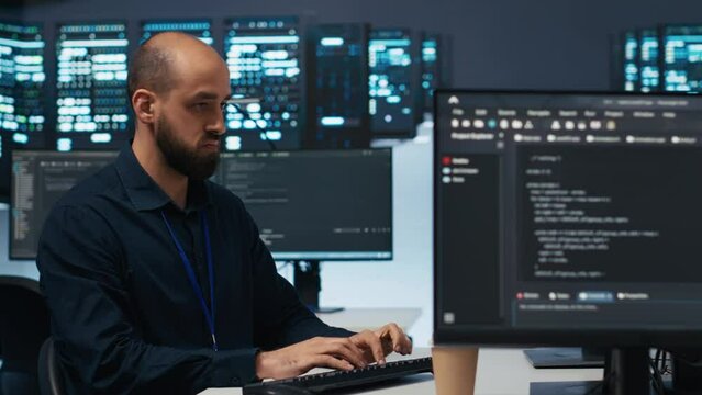 Technician using PC in high tech server hub facility to safeguard data from intruding hackers. Engineer protecting blade servers against unauthorized access, securing system from malicious traffic