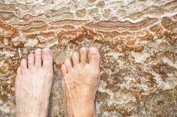 Human foot on the natural background of porous travertine stone