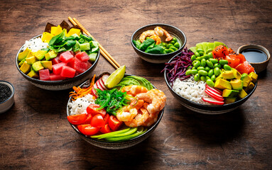 Poke bowls for balanced diet with vegetables, legumes, seafood, avocado and rice, wood table...