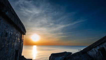 A beautiful sunset over the ocean with a small building in the background