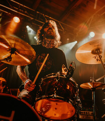 A tattooed drummer passionately plays his drum set under vibrant stage lights, delivering an energetic live performance filled with intensity and rhythm at a music concert.