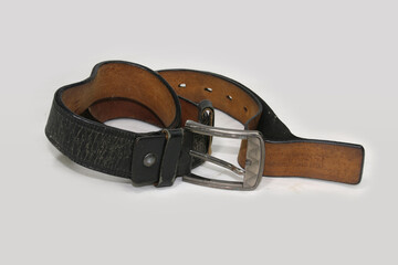 Obraz premium Used and Old black leather belt with buckle isolated on white background.