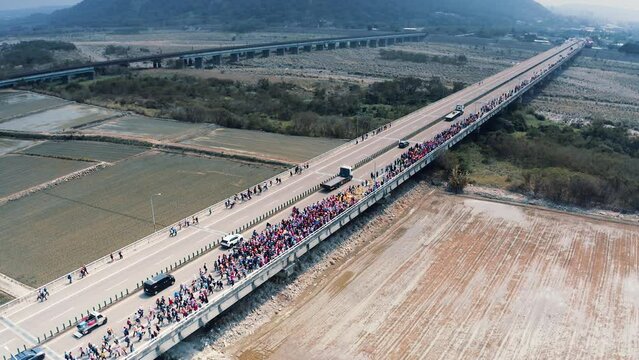 drone aerial shot of Baishatun Mazu Pilgrimage, a large crowd of people surrounding Mazu across the long bridge, wide shot visual extension of the scene, devout belief, Taoism Taiwan Asia