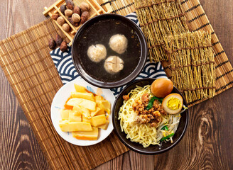 Chinese dry pasta noodles with Crispy bamboo shoots, meatballs soup, minced pork meat, preserved egg and chopsticks served in dish isolated on napkin top view on table taiwan food