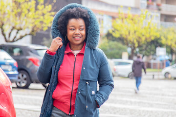 afro woman in winter jacket walking in the city