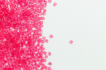Pink acrylic beads scattered on a blue background with copy space.