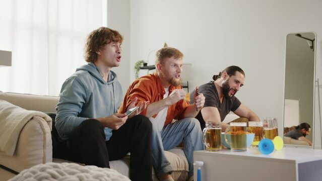 Group of fans watching football match on tv, drinking beer and eating chips, celebrating goal. European and World football cup, Germany, USA, Canada, Mexico. Sport and soccer fans. Slow Mo