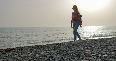 Young woman traveler goes walking along the sea