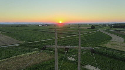 Power line pylon and telephone wires in rural countryside sunset setting. Aerial
