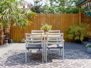 Minimalistic English modern garden with table and chairs. Sunny summers day with green plants and...