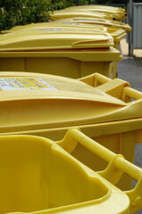 Poubelles jaunes de recyclage devant une copropriété