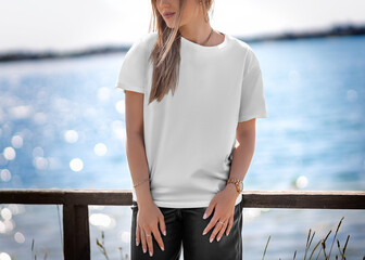Mockup of a white t-shirt on a blonde girl on the embankment, front view.