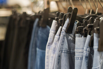 Row of jeans on the hanger in the shop, selective focus. Concept of buy, sale and denim fashion